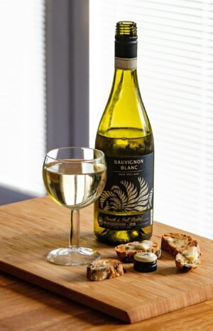 A bottle of Sauvignon Blanc paired with artisan bread and cheese on a wooden board.