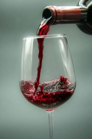 Elegant close-up of red wine being poured into a glass, highlighting the rich texture.