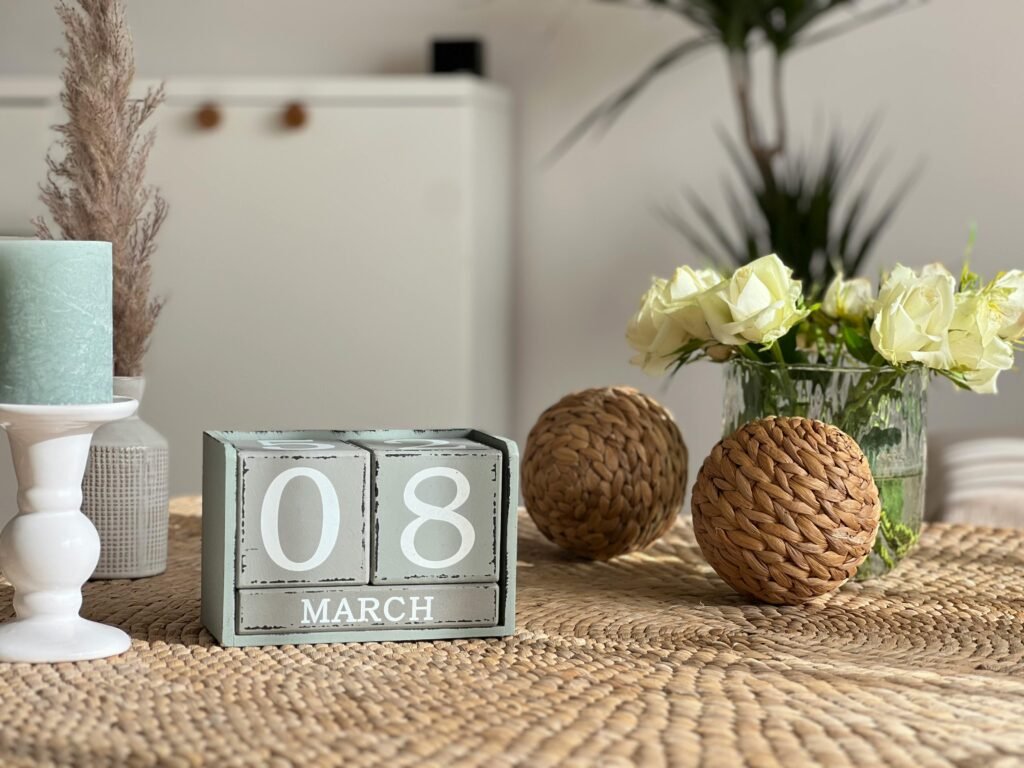 Cozy tabletop decor featuring March 8th calendar, flowers, and candle. Ideal for spring themes.