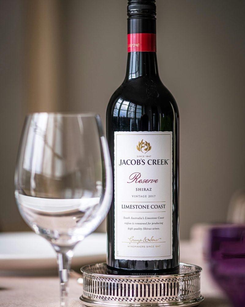 Close-up of wine bottle and glass on a dining table. Elegant dining setup indoors.